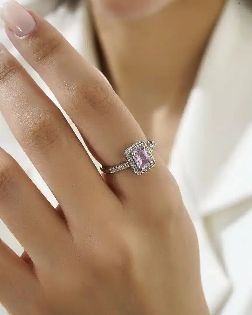 Pink-single gemstone-ring-xuping تصویری از یک حلقه نقرهای ظریف با نگین مستطیلی بنفش که با نگینهای ریز درخشان احاطه شده است. این انگشتر زیبا برای استایلهای رسمی و روزمره مناسب بوده و جلوهای لوکس و مدرن به دستان شما میبخشد.